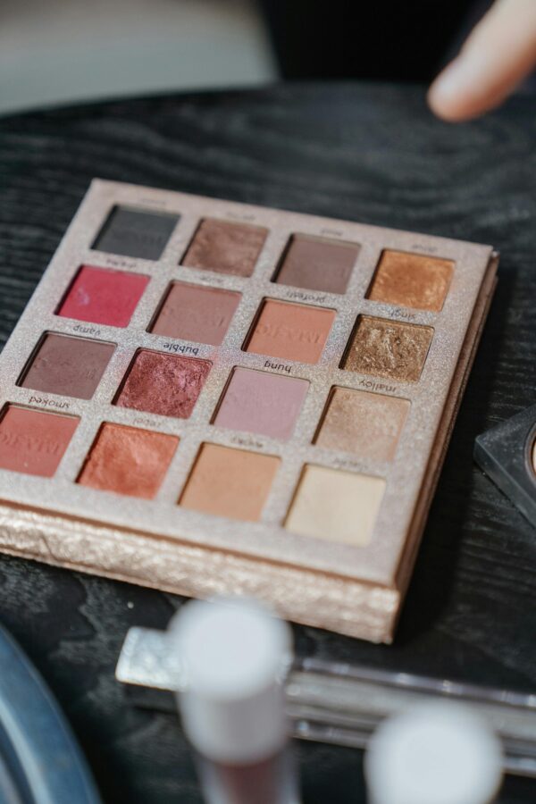 A vibrant eyeshadow palette with diverse colors on a black wooden surface, perfect for makeup enthusiasts.